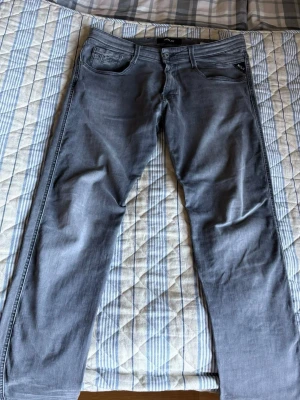 Gråa slim fit jeans från Replay - Snygga gråa slim fit jeans från Replay med klassisk femficksdesign och diskreta sömmar på bakfickan. Jeansen har normal midja och är tillverkade i mjukt denimtyg med lite stretch för extra komfort. Storlek 32/34