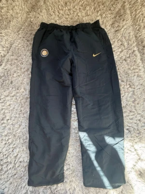 Nike Inter Milan track suit träningsbyxor Storlek M - ✅ Hela tracksuiten finns på min profil! (jackan) Säljer ett par svarta träningsbyxor från Nike med Inter Milan-logga på vänster sida och gul Nike Swoosh på höger. Dem är tillverkade i ett lätt, sportigt material som passar perfekt till träning eller fotboll, eller bara om du vill ha en riktigt skön tracksuit för kommande säsongerna! Riktigt bra kvalite. Nästan oanvända, toppskick