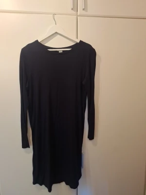 Marinblå långärmad klänning H&M Basic - En enkel och stilren mörkt marinblå klänning mes lång ärm från H&M Basic. Klänningen har rak passform, båthalsringning och en söm mitt bak.  Perfekt att styla med sneakers eller boots för en clean look. Märkt med storlek L men passar mig som normalt är en M.