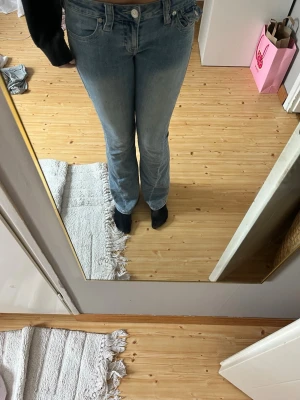 True religion jeans - Ett par snygga true religion lågmidjad boocut i modellen ”jocey” i fint skick förutom nere i benen där det är uppslitet men inget man ser. Säljer för det inte kommer till användning. I storlek 27.