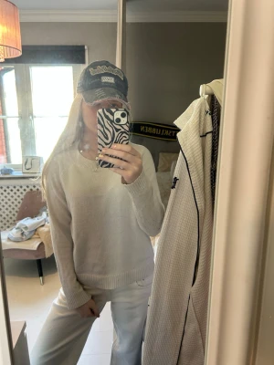 Vit stickad tröja i basic stil - Säljer en enkel och stilren vit stickad tröja med rund hals och ribbade muddar. Tröjan har en avslappnad passform och är perfekt att matcha med jeans eller kjol. Materialet känns mjukt och bekvämt mot huden.