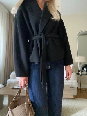 Stilren svart kort kappa  - Säljer en stilren svart jacka med knytbälte i midjan från & Other Stories🤍 Väldigt elegant modell som passar både till jeans och mer uppklädda outfits. Perfekt för höst och vår. Storlek S