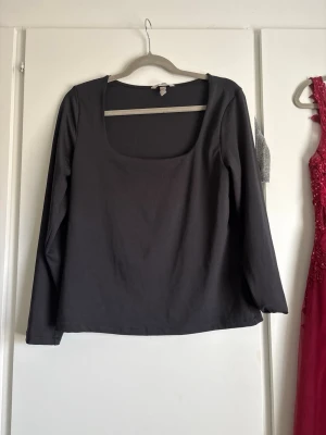 Svart långärmad topp med fyrkantig ringning - En stilren svart långärmad topp med fyrkantig ringning. Toppen har en enkel och clean design som passar till många olika looks.