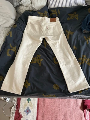 Vita raka jeans från Levi's - Säljer ett par vita jeans från Levi's med klassisk rak passform. W33 L32, sitter som 32/32. Någon liten fläck, se bilder
