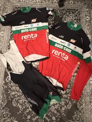 Cykelkit Trollhättans SOK - Säljer ett komplett cykelkit från Trollhättans SOK med kortärmad och långärmad cykeltröja samt bib shorts. Tröjorna är svart, röd, grön och vit med sponsorer tryckta på. Bib shorts är svarta med vita hängslen och gröna detaljer. Perfekt för cykling och träning. Storlek 164 