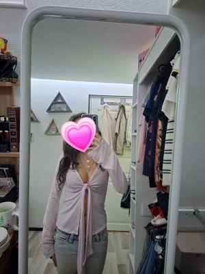 Ljusrosa topp - Säljer en fin ljusrosa topp med långa ärmar och djup v-ringning. Toppen har ett snyggt knyt framtill. Perfekt för dig som gillar en stilren men ändå jätte fin look. 