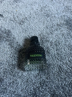 Valentino Uomo Born In Roma parfym - Valentino Uomo Born In Roma Green Stravaganza är en lyxig herrparfym i en mörkgrön, mönstrad glasflaska med svart kork. Förpackningen är svart med grön text och har en modern, edgy design. Perfekt för dig som gillar exklusiva dofter och snygga flaskor.