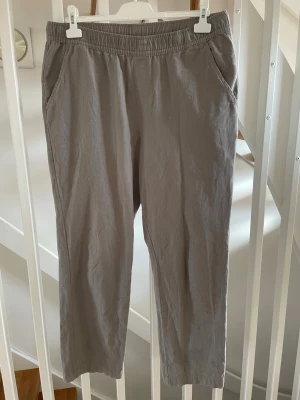 Grå linnebyxor XL - Snygga grå linnebyxor med avslappnad passform och resår i midjan. Storlek XL. Byxorna har två sidofickor fram och två bakfickor. Materialet är luftigt linne som ger en skön känsla och bomull så du slipper värsta skrynklet. 