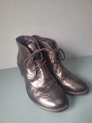 Italienska svarta läderkängor  / mormorskängor med snörning - Snygga svarta kängor i läder med klassisk snörning och dekorativa broguemönster längs kanterna. Skorna har en något spetsig tå och låg klack, perfekta för en stilren och edgy look. Passar till både jeans och kjol.