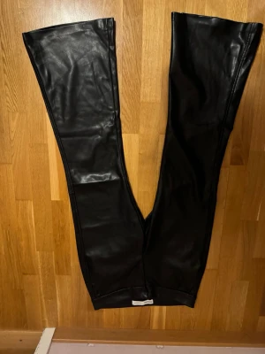 Svarta skinnbyxor från Bershka - Säljer ett par svarta skinnbyxor från Bershka. Byxorna har en stilren look och är tillverkade i mjukt skinnmaterial. Perfekta för dig som vill ha en edgy och trendig stil.