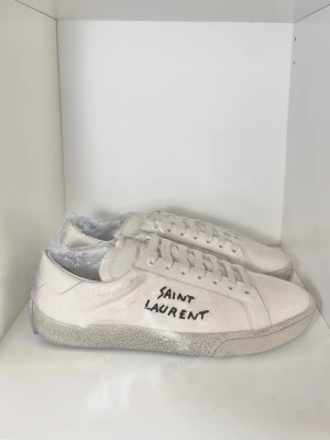 Saint Laurent Sneakers Vita sl06 - Stilrena och eftertraktade sneakers från Saint Laurent, perfekta sommarskon! Nyskick, inga defekter. Endast skor. Storlek 42,5 passar även 43. Kontakta mig för fler frågor och funderingar!