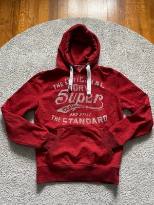 Röd Superdry Hoodie - Tjaaa!! Säljer denna riktigt fina och unika Superdry Hoodien. Väldigt bra skick och väldigt fin kvalité! Storlek M. Skriv gärna vid frågor eller funderingar😊