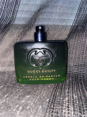 Gucci Guilty parfym - Gucci Guilty Absolu Pour Homme är en lyxig herrparfym i en stilren, rektangulär flaska med svart och grön toning. Flaskan har det ikoniska GG-emblemet i relief och guldfärgad text. Parfymen har sprayfunktion och flaskan är tillverkad i glas. Nypris är 1950kr denna är inprincip ny kanske 50-55 cl kvar!