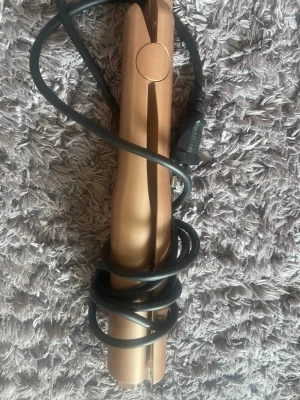 Guldigt plattång för hårstyling - Snygg plattång i metallic guld med slimmad design och spegelblanka plattor. Har en enkel on/off-knapp och flera värmeinställningar. Perfekt för att skapa raka eller vågiga frisyrer. Sladd medföljer och passar alla hårtyper.