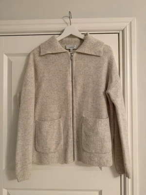 Stickad kofta från & Other Stories i 100% ull - Ljusgrå/melerad kofta från & Other Stories med dragkedja. Storlek S. 100% ull. Endast använd ett fåtal gånger och är därav i mycket fint skick! Superskön och mysig 🧸