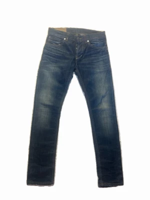 Blå slim fit jeans från Nudie Jeans - Snygga blå slim fit jeans från Dondup Jeans med klassisk femficksmodell och slitna detaljer. Extrem bra skick, jeansen är även en aning tjockare eftersom de är selvage! Storlek 29 vilket motsvarar ca 29:31!
