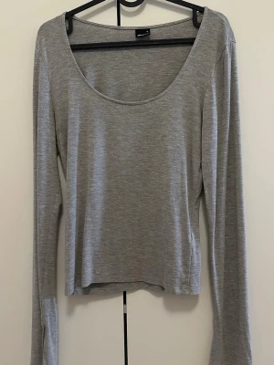 Grå långärmad med slit - Snygg grå långärmad med rundad urringning och slits vid ärmslutet. Soft touch från ginatricot.