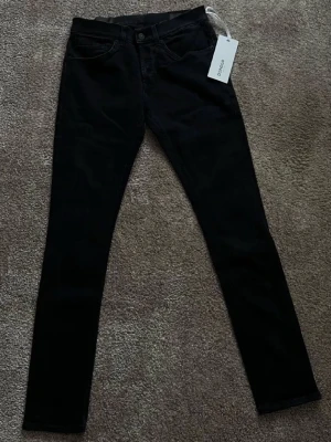 Svarta skinny jeans från Dondup - Snygga svarta skinny jeans från Dondup med klassisk femficksmodell och knappgylf. Jeansen har en smal passform och är tillverkade i stretchigt material för extra komfort. Perfekta för dig som gillar en stilren och modern look.