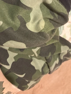 Camo shorts i bomull - Säljer ett par camouflagemönstrade shorts i mjuk bomull. De har klassisk grön, svart och beige camo-look och avslappnad passform. Perfekta för dig som vill sticka ut lite extra i sommar! Passar till streetwear eller chill dagar.