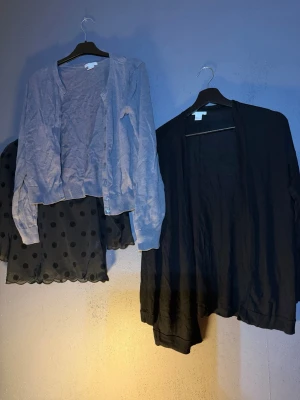 Två koftor och en meshtröja - Säljer ett paket med en ljusgrå kofta med knappar, en svart öppen kofta och en svart meshtröja med stora prickar. Perfekt för dig som gillar lager på lager och vill ha både basic och statement-plagg i garderoben.