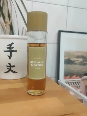 Mugwort Essence toner från I'm From - Mugwort Essence toner från I'm From i en genomskinlig glasflaska med olivgrönt lock och etikett. Tonern har en ljusbrun färg och innehåller extrakt av gråbo för att lugna och återfukta huden. Perfekt för dig som vill ha en naturlig och fräsch känsla i din hudvårdsrutin.