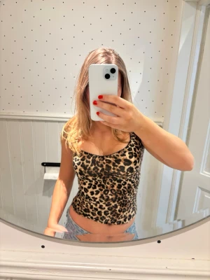 Leopardmönstrad topp från Nelly - Säljer en leopardmönstrad topp från Nelly med tight passform och bred urringning. Toppen är ärmlös och har ett stretchigt material som sitter snyggt på kroppen. Perfekt för dig som gillar djurmönster och vill sticka ut.
