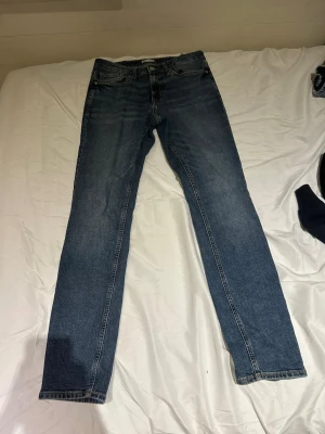 Blå raka jeans från Cubus - Snygga blå jeans från C i rak modell med klassisk femficksdesign. Jeansen har gul kontrastsöm och normalhög midja. Perfekta för dig som gillar en tidlös och avslappnad stil. Materialet är klassisk denim i bomull.