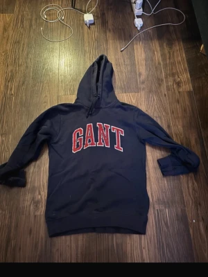 GANT HOODIE - Säljer denna snygga gant hoodie! Marin blå med röda detaljer, denna är ganska använd men texten har lossnat i tvätten men den har mycket kvar att ge! Den är storlek M men sitter mer som S. Nypris ligger runt 1000kr skick 8.5/10. Hör av dig vid intresse!