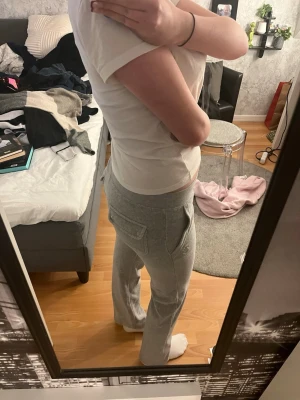 Juicy Couture 💞 - Säljer ett par grå mjukisbyxor med raka ben och stora fickor på sidorna. Byxorna har resår i midjan för extra komfort och är perfekta för chill dagar hemma. Materialet är mjukt och skönt, troligtvis bomullsblandning. Passar dig som gillar en avslappnad stil. En av knapparna är lite dålig men det är inget man märker eller tänker på iallafall för mig💞