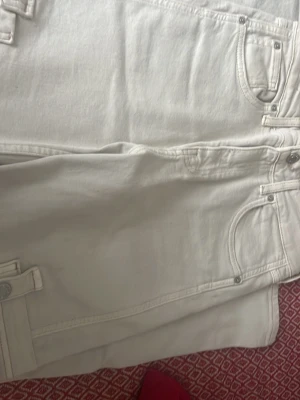 Beige raka jeans med fickdetaljer - Säljer ett par beige jeans med raka ben och coola fickdetaljer fram. Jeansen har klassisk femficksmodell och är gjorda i ett kraftigare denimtyg. Perfekta för dig som vill ha en clean och stilren look. Har inte använt den så mycke 