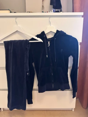Mörkblå velour mjukisbyxor Juicy Couture - Säljer ett par mörkblå mjukisbyxor i mjuk velour från Juicy Couture. Byxorna har en klassisk rak passform och matchar perfekt med en hoodie i samma material. Perfekt för dig som gillar en avslappnad och trendig stil.