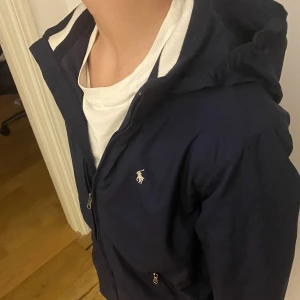Ralph Lauren Windbreaker - En sjukt fet windbreaker från ralph lauren i bra skick, perfekt för hösten. Storlek XS, passar mellan 160-170. Den enda lilla defekten är storlekslappen som blivit bortklippt men inget som syns eller märks. Hör av er vid frågor!