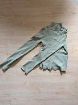 Ljusgrön ribbad polotröja - Trendig ljusgrön ribbad polotröja med lång ärm och hög hals. Perfekt att styla med jeans eller kjol för en snygg vardagslook.