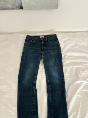 Mörkblå Acne Jeans - Säljer ett par vintage blå jeans från Acne Jeans med en slim/staright passform och  femficksdesign. Jeansen har snygga kontrastsömmar och fades. Storleken är 28/32, men passar ungefär 28/30. Jeansen är i super fint skick och har inga defekter.