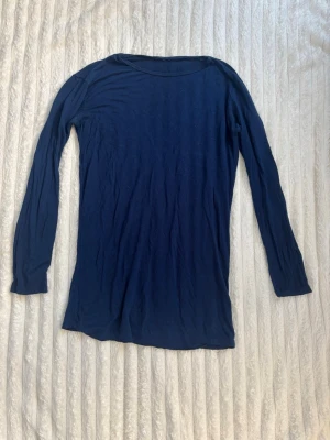 Marinblå långärmad topp  - En enkel och stilren marinblå långärmad topp. Toppen har rund halsringning och är gjord i mjuk bomull som känns skön mot huden. Perfekt att matcha med jeans eller kjol för en clean look.