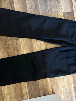 Svarta mjukisbyxor från 157 - Svarta mjukisbyxor från 157 med elastisk midja och raka ben. Byxorna har bakfickor och är tillverkade i mjukt bomullsmaterial som är perfekt för chill eller träning. Klassisk och enkel design som funkar till det mesta.