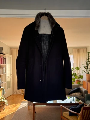 Herno kappa med bäver krage  - Snygg marinblå kappa från Herno med mjuk kanadensisk bäver på kragen och quiltat innerfoder. Klassisk rak passform och dolda knappar framtill. Perfekt för kalla dagar och tillverkad i Italien. Stilsäker och tidlös design som passar till många outfits. Nypris runt 14000kr, väldigt bra skick.