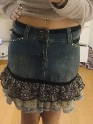 Jeanskjol med volang och söta detaljer  - En kort jättesöt jeanskjol med nitar vid fickorna, volanget nertill och svart sammetsdetalj. Den är köpt secondhand och är i storlek M men är lite liten i storlek. Skriv om frågor eller fler bilder. ☺️💖