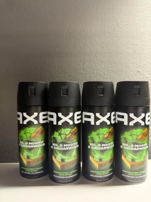 AXE Wild Mojito & Cedarwood spray Antal 4.  - Fyra flaskor AXE Wild Mojito & Cedarwood body spray med svart och grön design. Doften kombinerar fräscha mojito-noter med träiga inslag av cederträ. Flaskorna är cylindriska med tryckknapp och har tydlig logotyp framtill.