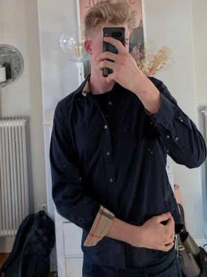 Svart skjorta från Burberry - En skjorta från Burberry. Det är toppen skick på skjortan. använd 2 gånger pga för liten. Om du har fler frågor är det bara att ställa🤝☺️ Skjortan passar garanterat folk i M