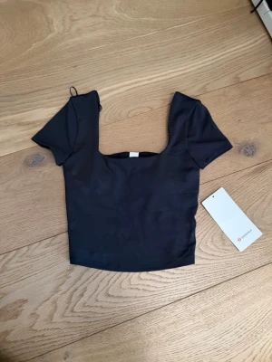 Svart croppad topp från Lululemon - Trendig svart croppad topp från Lululemon med korta ärmar och fyrkantig urringning. Toppen är oanvänd! Jätte söt top, som kan kombineras med allt🩷🩷 priset kan diskuteras