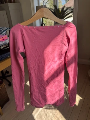 Rosa långärmad karisma topp - En jättefin somrig och lite mörkare rosa topp från det italienska märket karisma. Jag råkade missfärga den en gång pyttelite men annars väldigt fin färg och det syns knappast. perfekt för konståkning träningar på och utanför isen. Toppen har även kristaller på ryggen som glittrar. Tyvärr har lite av sömmen gått upp i armhålan och lite nopper även där men det är inget man ser tydligt.😊Jag älskade den!