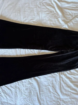 Svarta mjukisbyxor i velour - Säljer ett par svarta mjukisbyxor i mjuk velour med resår och dragsko i midjan. Byxorna har raka ben och en skön, avslappnad passform. Perfekta för chill dagar hemma eller när du vill vara extra bekväm.