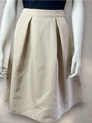 Vila Linjeformad kjol  - Snygg beige linjeformad kjol med breda veck framtill. Kjolen har hög midja och är tillverkad i ett mjukt material som ger ett stilrent och klassiskt intryck. Perfekt för dig som vill ha en enkel men elegant look. #kjol #vila 