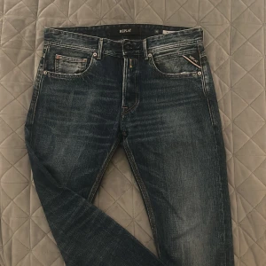 Blå jeans från Replay - Snygga blå jeans från Replay med klassisk femficksdesign och subtila slitningar. De har en knappgylf och märkeslogga på baksidan. Perfekta för en avslappnad stil. Ny skick förutom översta knappen har låstnat(se bild 4), enkelt att fixa. -pris kan diskuteras! 