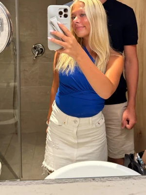 Blå oneshoulder body  - Snygg blå oneshoulder topp med draperad effekt och tight passform. Perfekt för dig som vill ha en trendig och stilren look. Toppens material känns mjukt och stretchigt, vilket gör den bekväm att bära hela dagen.