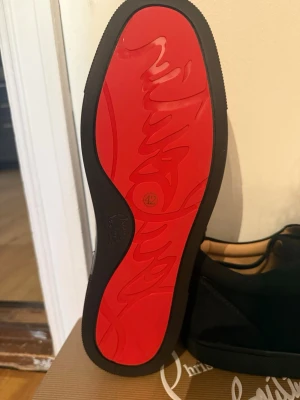 Christian Louboutin svarta sneakers - Säljer ett par exklusiva svarta sneakers från Christian Louboutin med den ikoniska röda sulan och snygg design. Skorna är tillverkade i högkvalitativt material och har en låg profil. Perfekt för dig som vill sticka ut med stil och lyx.