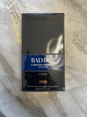 Bad Boy Cobalt parfym 50ml - Bad Boy Cobalt från Carolina Herrera är en Eau de Parfum Elixir i en elegant svart och mörkblå förpackning. Flaskan rymmer 50 ml och har en modern, stilren design som känns lyxig och maskulin. Perfekt för dig som gillar exklusiva dofter.