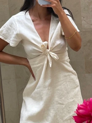 Studentklänning  - Tie Front Linen Dress Oandvänd kort klänning i färgen ”Cream” i  materialet linne med v-ringad front och knyt detalj. Lite skrynklig då den tyvärr bara hamnat i garderoben då jag valde en annan student klänning. 