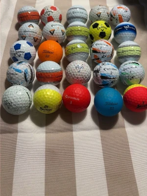 Färgglada golfbollar från olika märken - Samling med 20 golfbollar i olika färger och mönster från märken som TaylorMade, Titleist, Callaway och Srixon. Bollarna är vita, röda, blå, orange, gula och har olika tryck och logotyper. Perfekt för dig som vill ha variation på golfbanan.